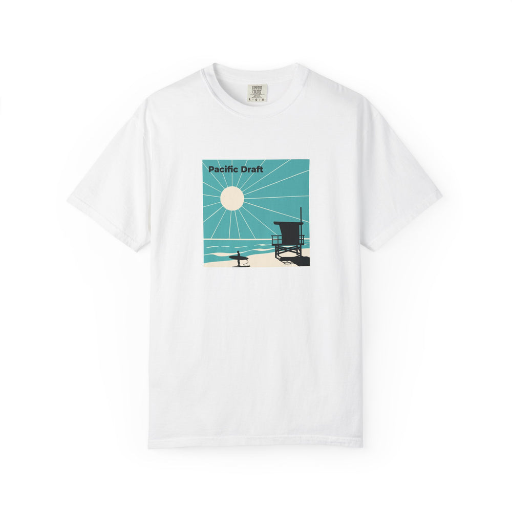 White T-shirt with a turquoise and cream Pacific Draft panel showing sun rays, a lifeguard tower, and a surfer printed on the front.